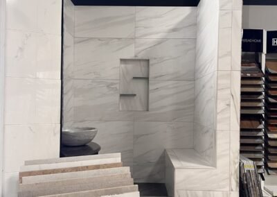 White marble look porcelain shower display with niche and bench in Evansville IN